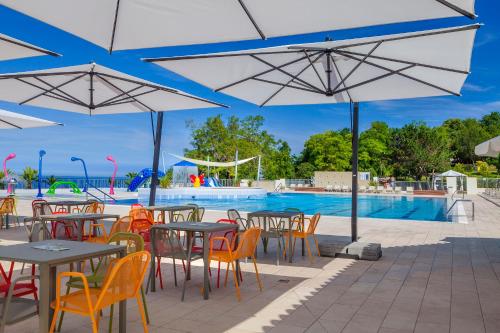 an outdoor patio with tables and chairs and a pool at Happy Camp Mobile Homes in Valamar Camping Lanterna in Poreč
