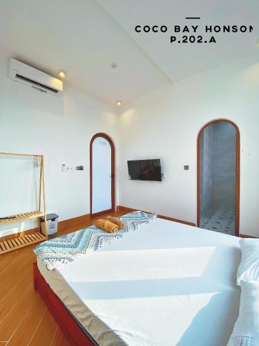 a large white bed in a room with a flat screen tv at Coco Bay Hon Son in Lai Sơn