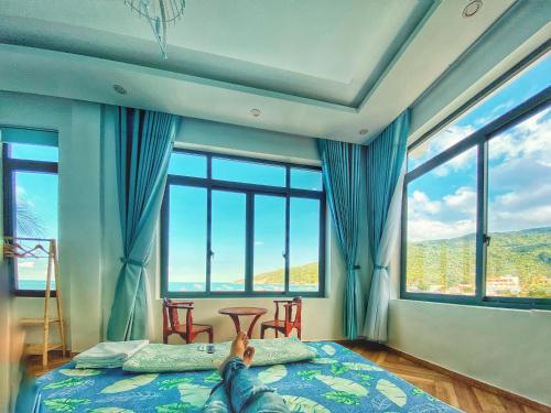 a person laying on a bed in a room with windows at Coco Bay Hon Son in Lai Sơn