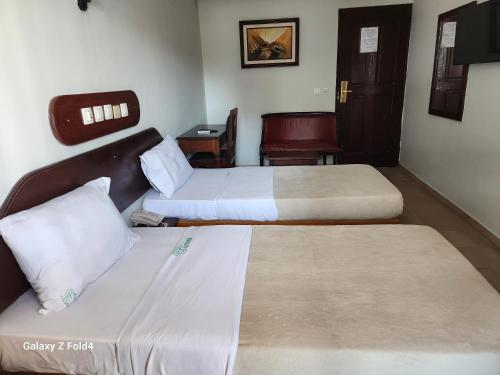 a hotel room with two beds and a chair at Golden Hôtel in Abidjan
