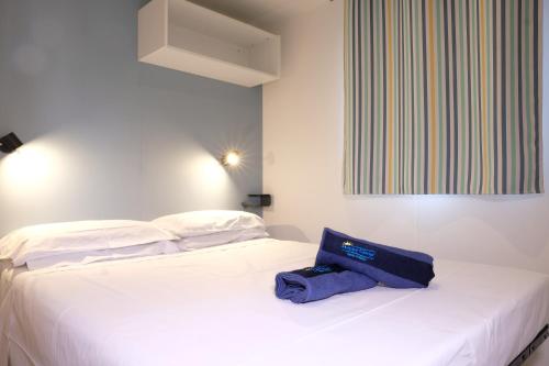 a white bed with a blue bag sitting on it at Happy Camp Mobile Homes in Valamar Camping Lanterna in Poreč