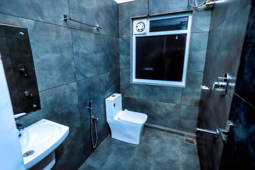 a bathroom with a toilet and a sink and a window at La Vista Resorts in Wayanad