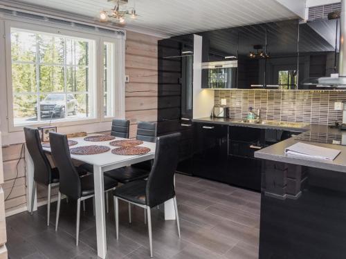 eine Küche mit einem weißen Tisch und schwarzen Schränken in der Unterkunft Holiday Home Kiehtäjän kuohu by Interhome in Käylä