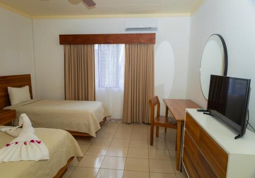 a hotel room with two beds and a flat screen tv at Hotel Las Espuelas, Bar & Restaurant in Liberia