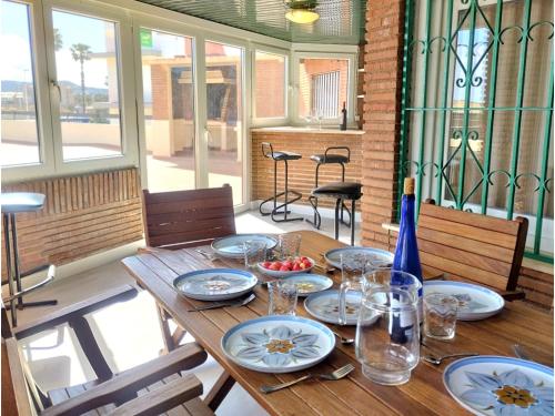 a wooden table with plates and glasses on it at Apartment Las Pergolas-2 by Interhome in Jávea