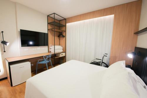a bedroom with a bed and a desk with a television at ibis Curitiba Shopping in Curitiba