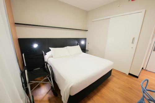 a bedroom with a large white bed and a chair at ibis Curitiba Shopping in Curitiba