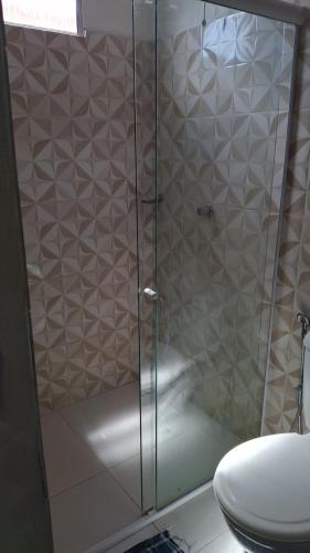 a shower with a glass door next to a toilet at J&m hospedagem in Marau