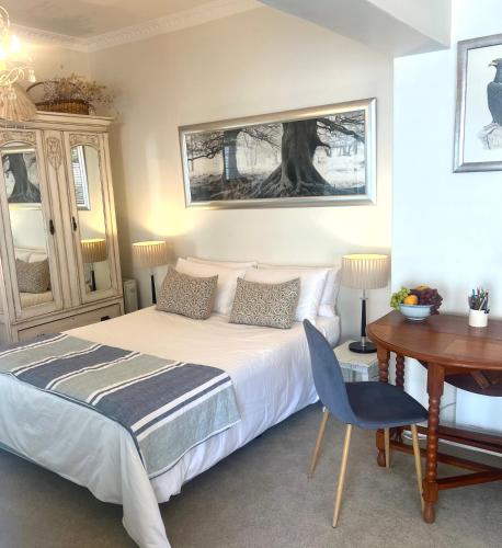 a bedroom with a bed and a table and a desk at Cape Town Explorer's Rest in Meadowridge