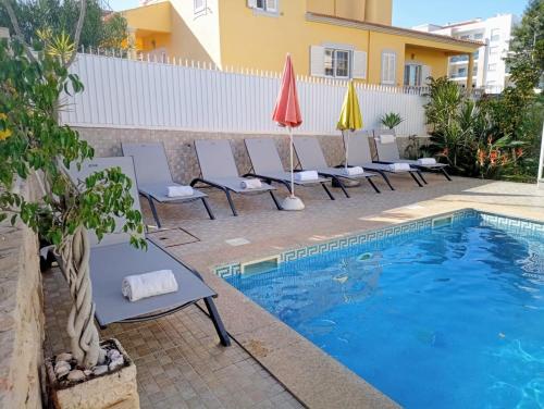 a group of chairs and umbrellas next to a swimming pool at Vivenda Luz - Jacuzzi & Swimming Pool in Albufeira
