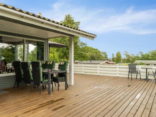 a wooden deck with a table and chairs on it at Holiday Home Blomma - 300m from the sea by Interhome in Humble