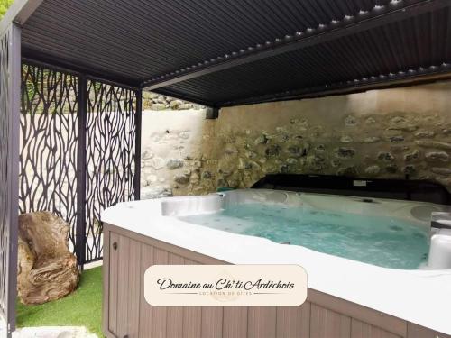 un bain à remous dans un jardin avec un bâtiment dans l'établissement Gite de groupe - Domaine au Ch'ti Ardéchois, à Rochessauve