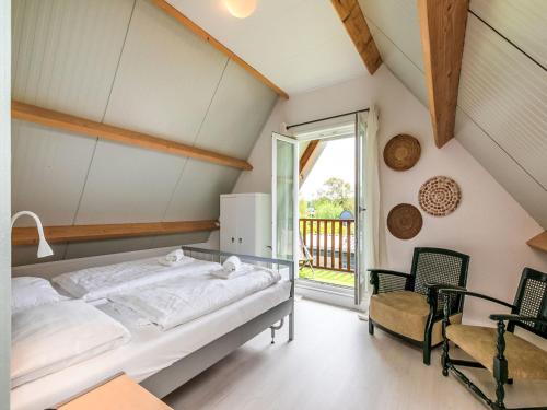a bedroom with a bed and two chairs and a window at Holiday Home Horizon- Sea & Sun by Interhome in Renesse