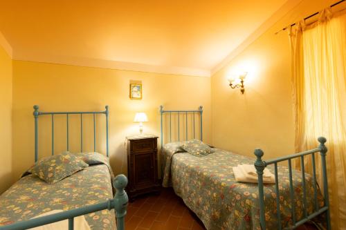 a bedroom with two beds and a lamp and a window at Fattoria Poggio Capponi in Montespertoli