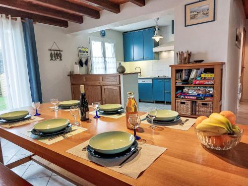 - une table en bois avec des assiettes et des verres dans la cuisine dans l'établissement Holiday Home Charme de la Grande Bosse by Interhome, à LʼÉpine