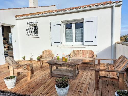 eine Holzterrasse mit Stühlen und einem Tisch in der Unterkunft Holiday Home Charme de la Grande Bosse by Interhome in LʼÉpine