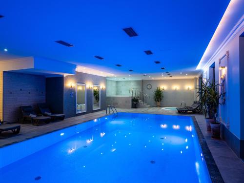 a large swimming pool with a blue lighting at Hotel Paryski Art & Business Zakopane - Basen Jacuzzi Sauna Małpi Gaj in Zakopane