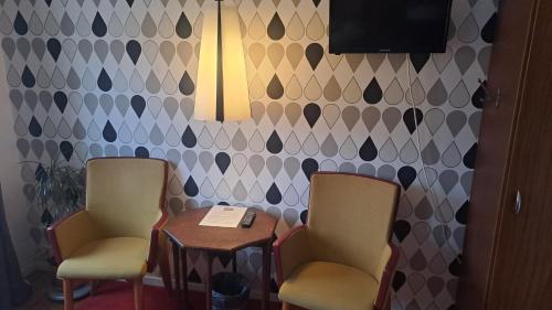 two chairs and a table in a room with a wall at Sveriges minsta Hotell! Hôtel Gruyère in Landskrona