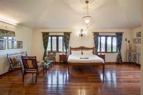 a bedroom with a bed and two chairs in it at Away From Home - 2 - Home Stay Ooty, Entire 4BHK Villa in Ooty