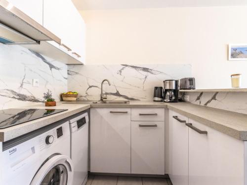 - une cuisine blanche avec lave-linge et sèche-linge dans l'établissement Apartment Le Sunset-Cap Sud-26 by Interhome, au Cap d'Agde