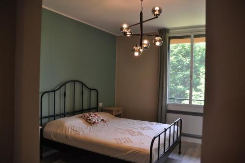a bedroom with a bed with a chandelier and a window at Nova Acacie Mi3 - Entire Apartment in Basiglio