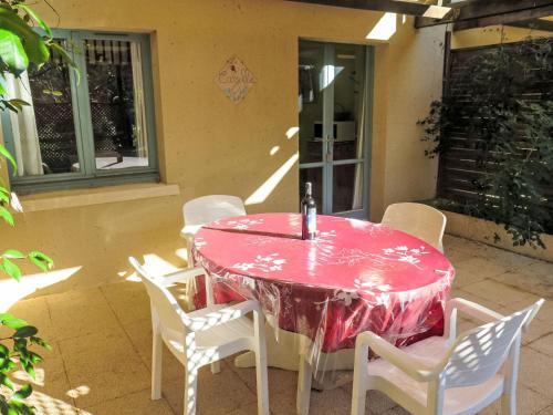 - une table rouge avec des chaises blanches sur la terrasse dans l'établissement Holiday Home Le Cazelle by Interhome, à Gindou