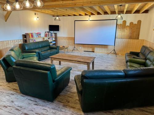 a living room with leather furniture and a screen at Le Clos des 4 Bastides in Saint-Eutrope-de-Born