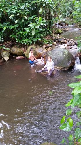 three people sitting in the water in a river at Hotel Campestre Villa Nico in Bochalema
