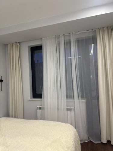 a bedroom with white curtains and a window at An hotel in Yerevan