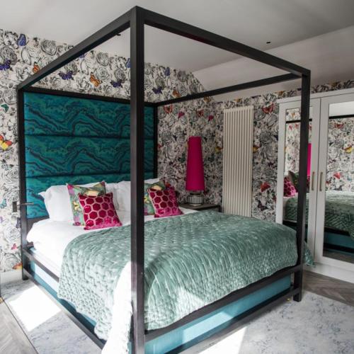 a bedroom with a canopy bed with pink pillows at Dewars Restaurant and Rooms in Malton