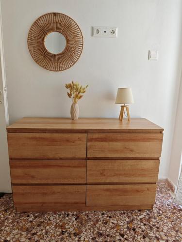 a wooden dresser with a lamp and a mirror at Aspa and Alex penthouse retreat in Koropíon