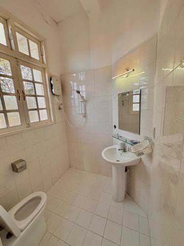 a white bathroom with a toilet and a sink at Hùng Nam House in Khu Chi Lăng