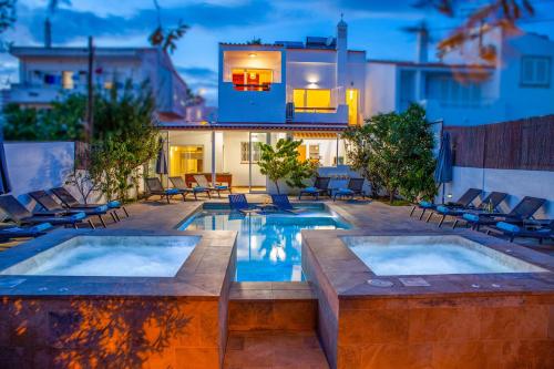 a backyard with two pools and chairs and a house at Villa Palancar by Algarve Vacation in Albufeira