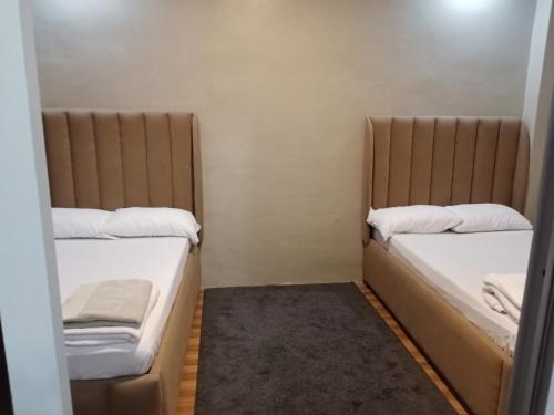 a small room with two beds with white sheets at Baverlly Home Stay in Cotabato
