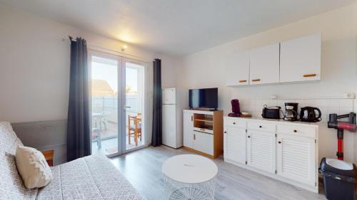 une cuisine avec des armoires blanches et une table dans une pièce dans l'établissement La Pause Oceane, à Bretignolles-sur-Mer