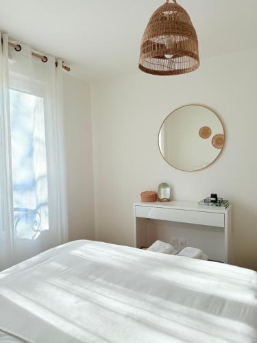 a white bedroom with a bed and a mirror at Cozy apartment near Paris in Clamart