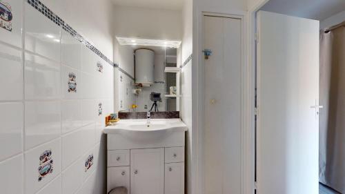 une salle de bain blanche avec un lavabo et un miroir dans l'établissement La Pause Oceane, à Bretignolles-sur-Mer