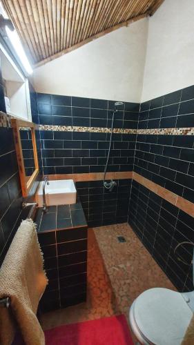 a bathroom with a toilet and a black tiled wall at LE BENTENIER Home Détente in Nianing