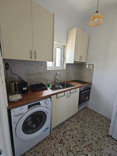 a kitchen with a washing machine and a sink at Aspa and Alex penthouse retreat in Koropíon