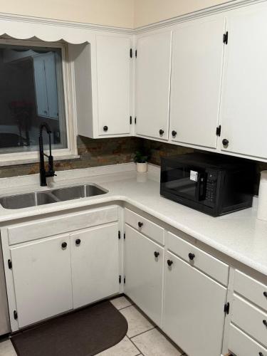 a kitchen with white cabinets and a sink and a microwave at The Gather Grove in Toledo