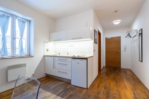 a kitchen with white cabinets and a sink and a window at Mitte Apartments in Brno