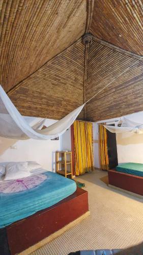 a bedroom with two beds and a straw roof at LE BENTENIER Home Détente in Nianing