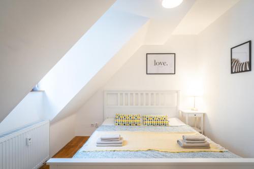a white bedroom with a bed in a attic at Mitte Apartments in Brno