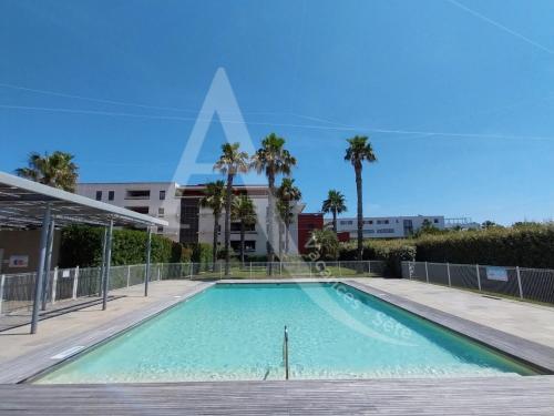 - une piscine dans un bâtiment avec des palmiers dans l'établissement Plage de Villeroy, 4 personnes, ascenseur, parking et terrasse, à Sète