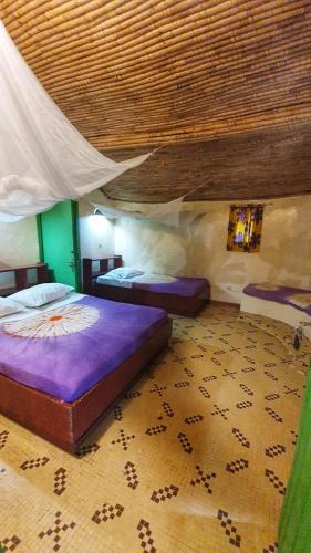 a bedroom with two beds and a wooden ceiling at LE BENTENIER Home Détente in Nianing