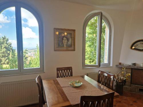 a dining room with a table and three windows at Secret villa's city garden in Perugia