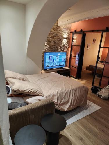 une chambre avec un lit et une télévision à écran plat dans l'établissement Escapade sur la Sorgue, à LʼIsle-sur-la-Sorgue