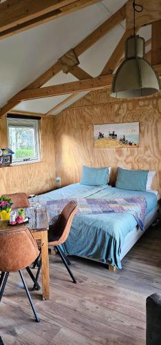 a bedroom with a large bed and a table at B&B ZusenZomer in Oostwoud
