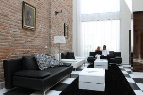 two people sitting in a living room with a brick wall at Hotel Castello & Thermal Spa Siklós in Siklós