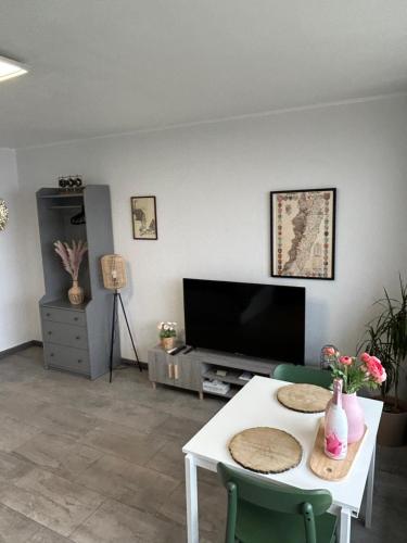 un salon avec une table et une télévision dans l'établissement Le Panorama - GÎTES MARCK, à Turckheim